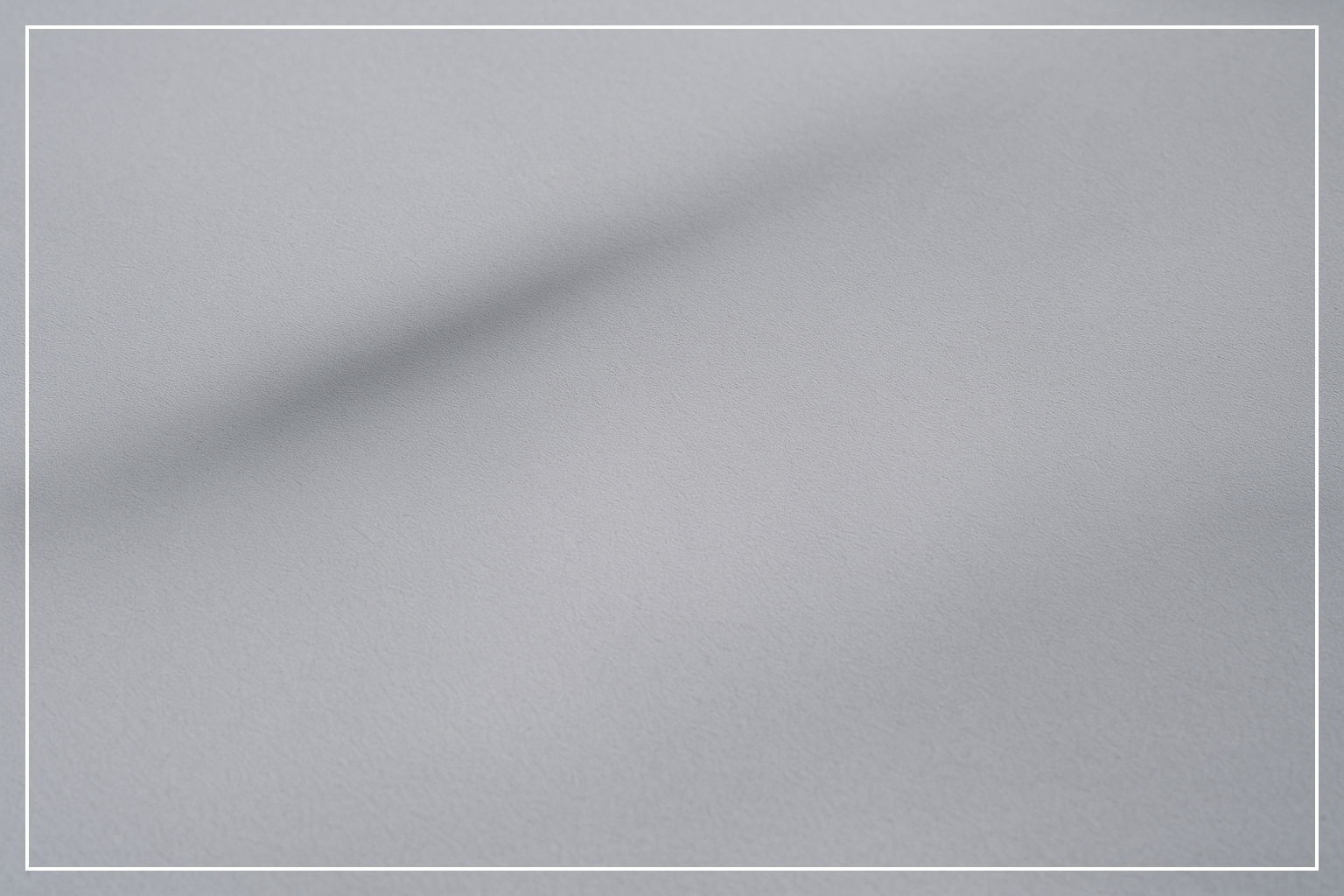 Graue minimalistische Oberfläche, weicher Schatten, kühle ruhige Textur, ohne Menschen.